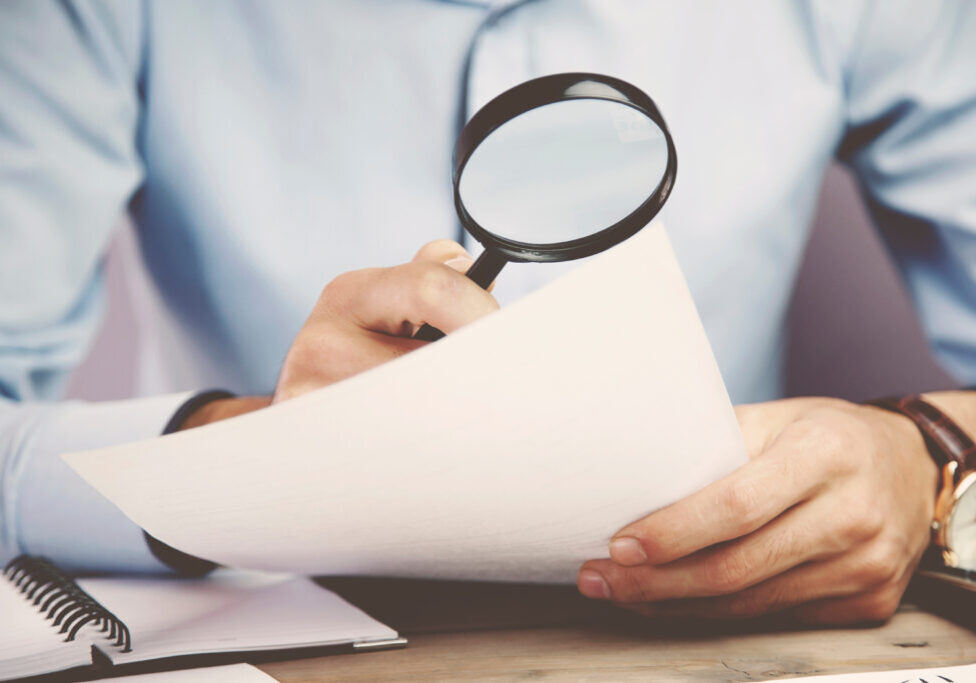 Businessman looking through a magnifying glass to documents