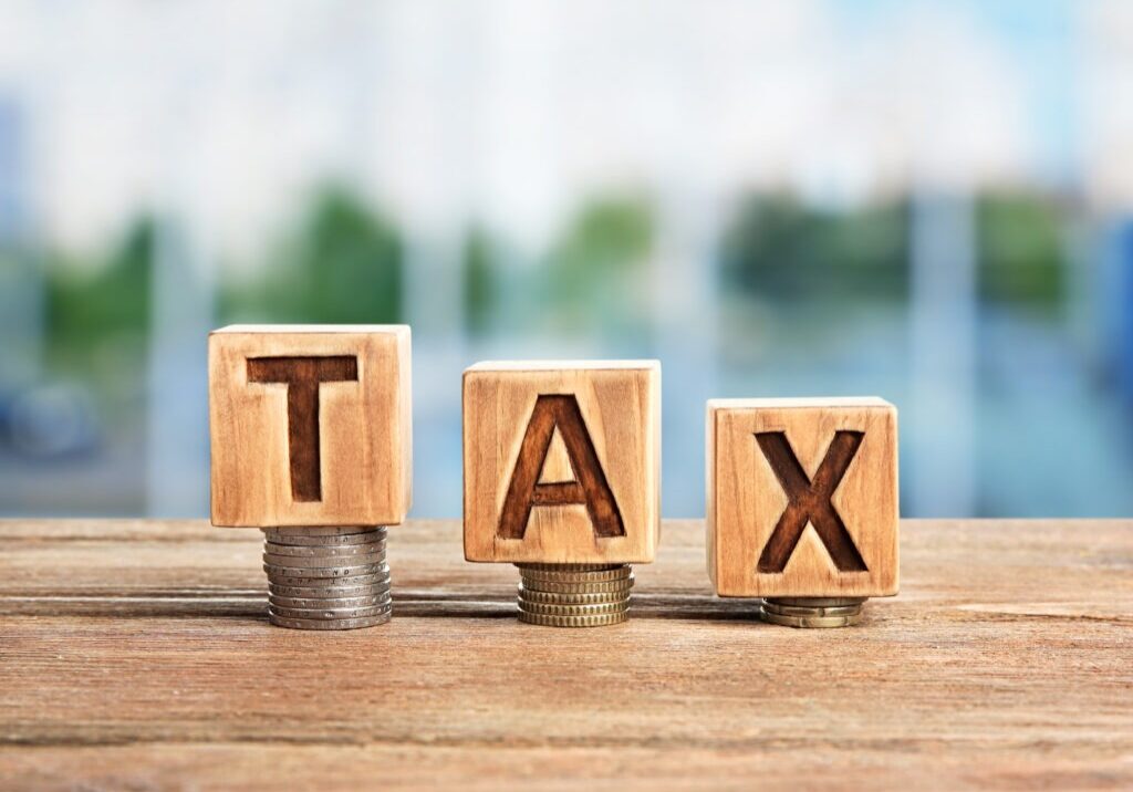 Word tax on wooden blocks with stacked coins. Financial concept.