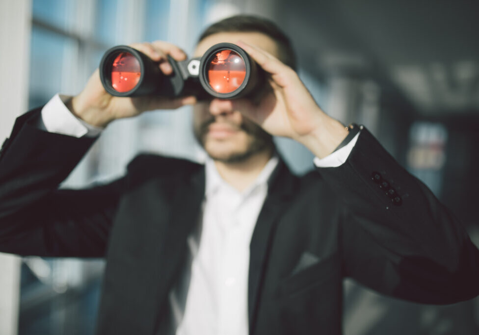 american businessman using binoculars in office