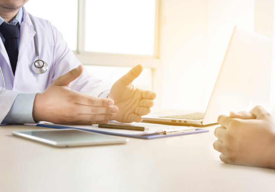 doctor  taking patient are discussing something in hospital on computer in doctors office close up