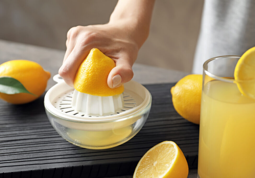 Woman squeezing lemon juice in kitchen