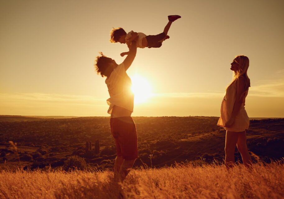 Happy family having fun playing at sunset on summer nature.