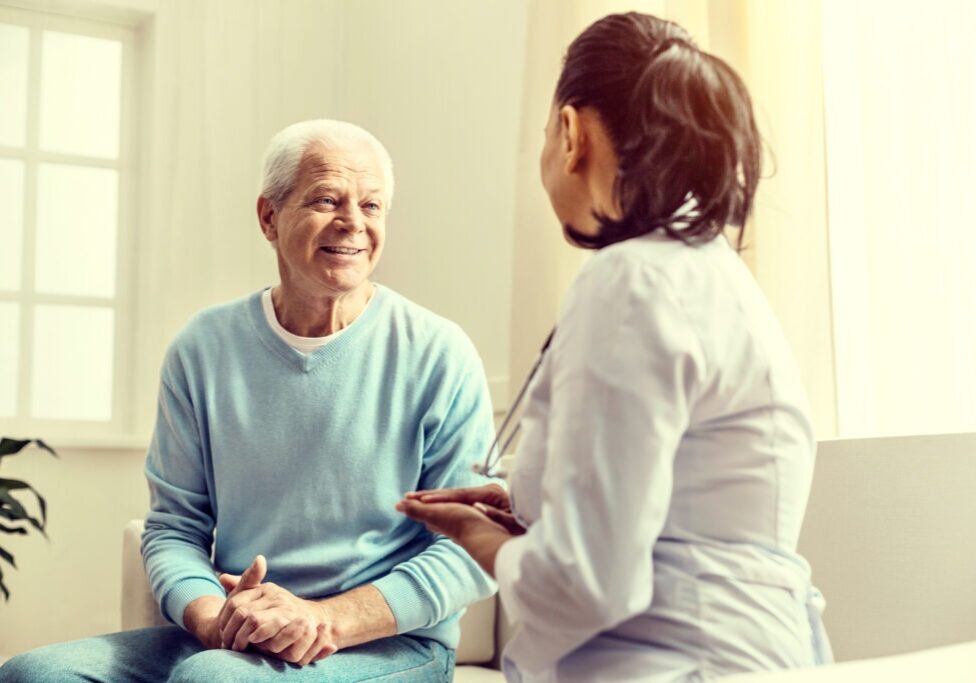 Staying positive. Selective focus on a happy retired man beaming while sitting next to his doctor and talking with her during a consultation.