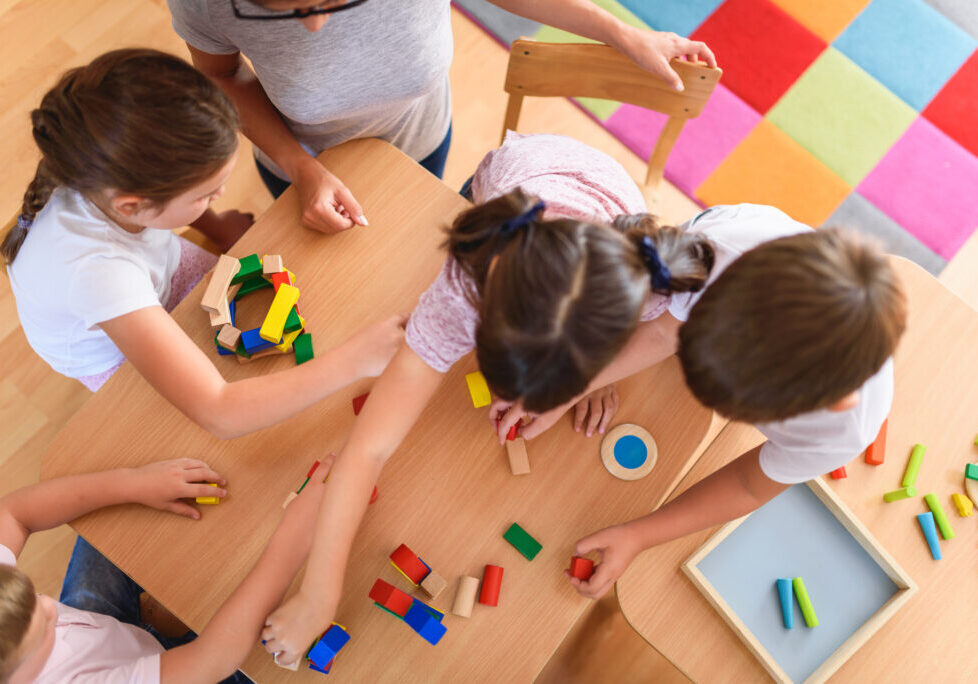 Preschool teacher with children playing with colorful wooden did