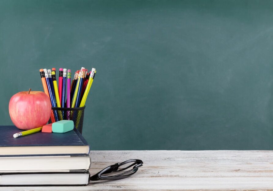 Back to school concept including books and stationery supplies with green chalkboard