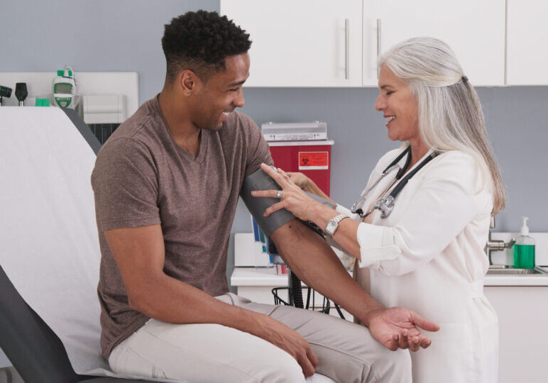 Mature white female physician checking male patients blood pressure at clinic