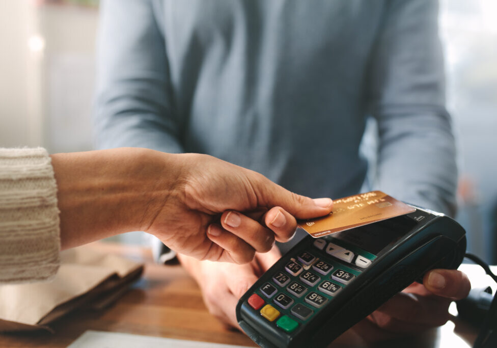 Pharmacist accepting credit card by contactless payment.  Woman purchasing products in the pharmacy. Pharmacist hands charging with credit card reader.