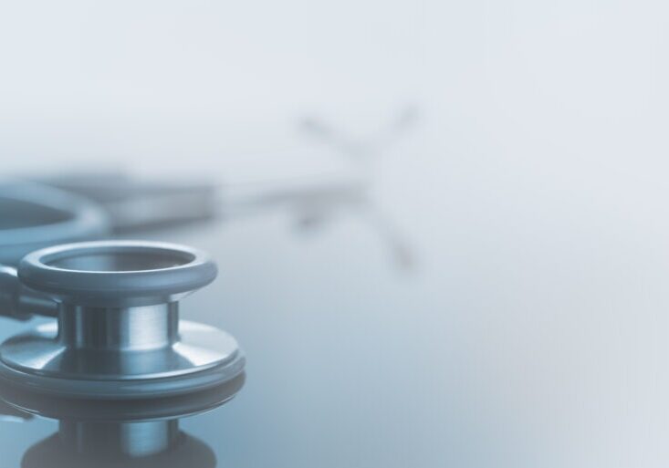 Medical background, Close up stethoscope on glass table with reflection and copy space, monotone, soft background.