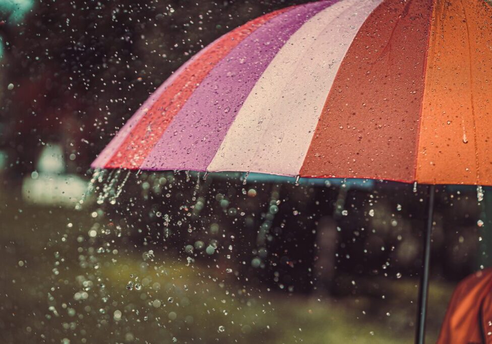 Bright colored rainbow umbrella in the rain autumn weather