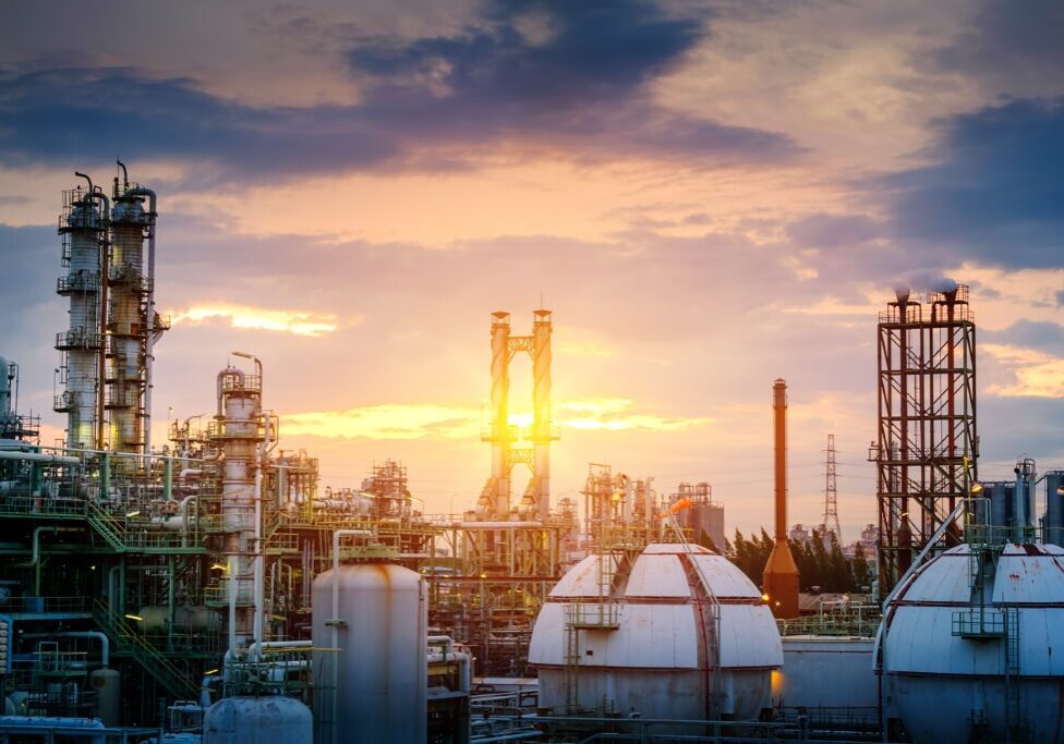 Manufacturing of oil and gas refinery industrial or Petrochemical industry plant on sunset sky background with smoke stacks and gas sphere tanks