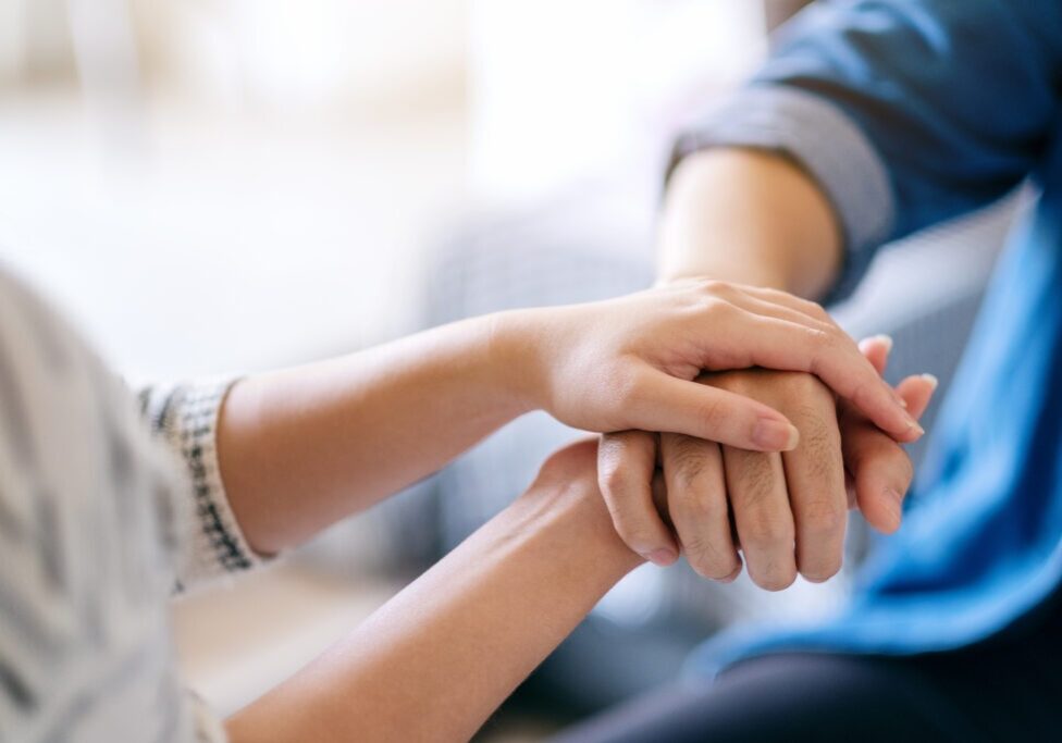 A man and a woman holding each other hands for comfort and sympathy