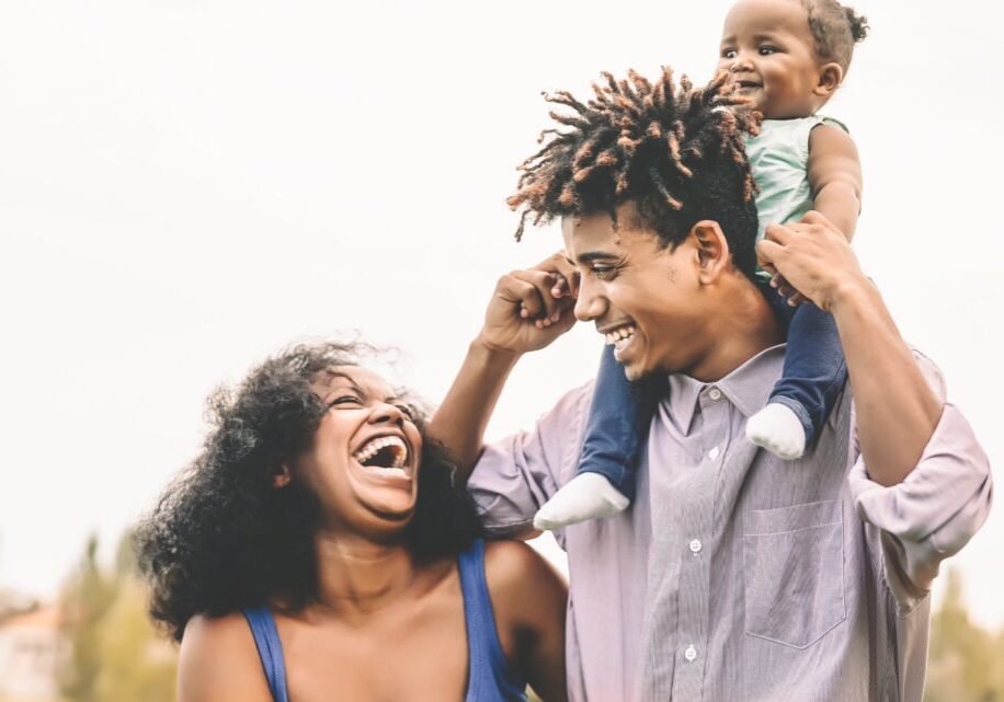Happy African family having fun in public park - Father mother and little daughter enjoying time and laughing together - Love and parenthood concept