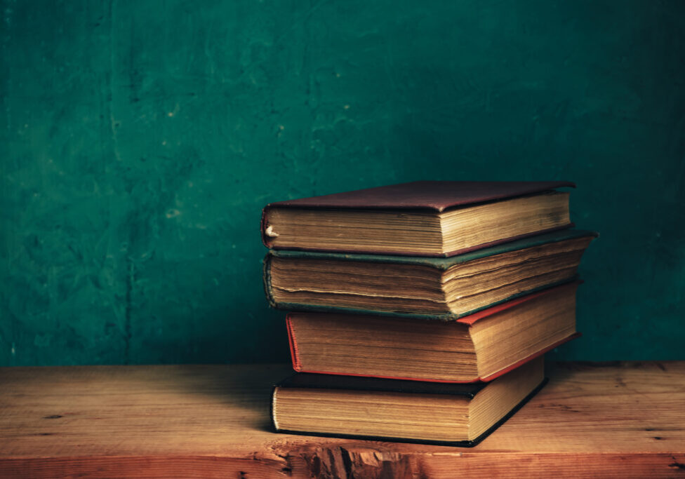 Old books on a old red wooden table. Beautiful Green wall background.