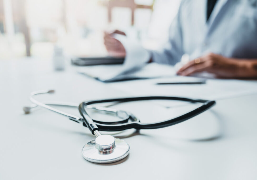 Doctor typing information on Laptop in Hospital office focus on Stethoscope