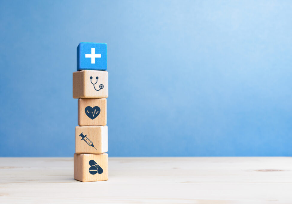 Health insurance concept, wooden blocks with healthcare medical icons on blue background, copy space