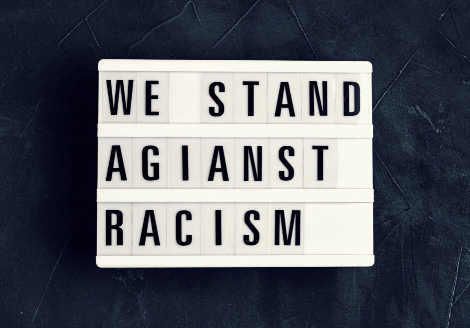 We stand against racism text on light box over dark background