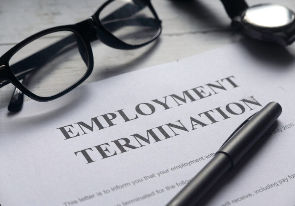 Selective focus of glasses,watch,pen and Employment Termination letter on a white wooden background.