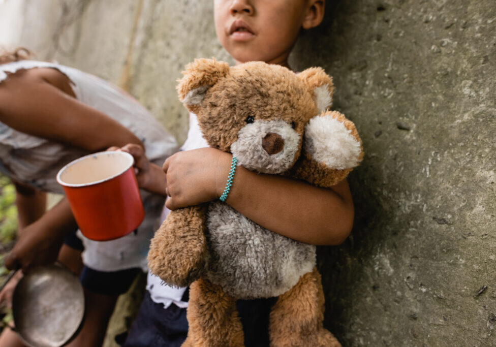 Cropped view of homeless african american children with dirty teddy bear begging alms in slum