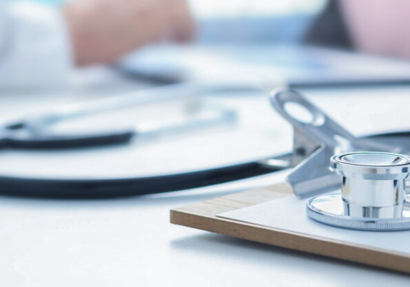 Stethoscope and clip board on the doctor workplace close up