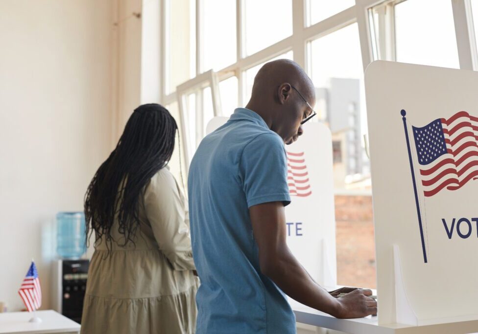 Back view portrait of young African-American people standing in voting booth and thinking, copy space