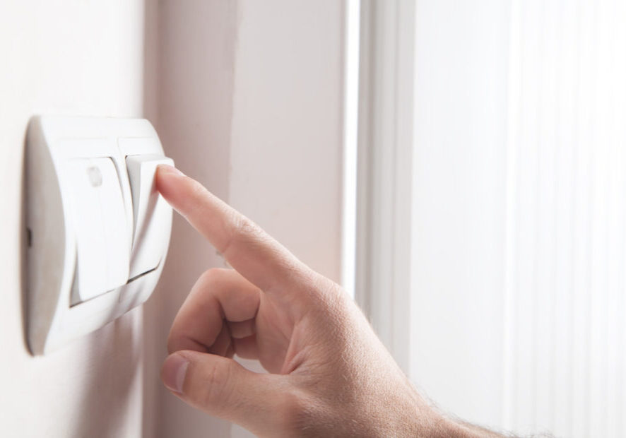 Hand turning off on light switch.