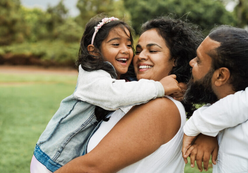 Happy indian family having fun outdoor - Hindu parents laughing with their children at city park - Love concept - Main focus on mother and daughter face