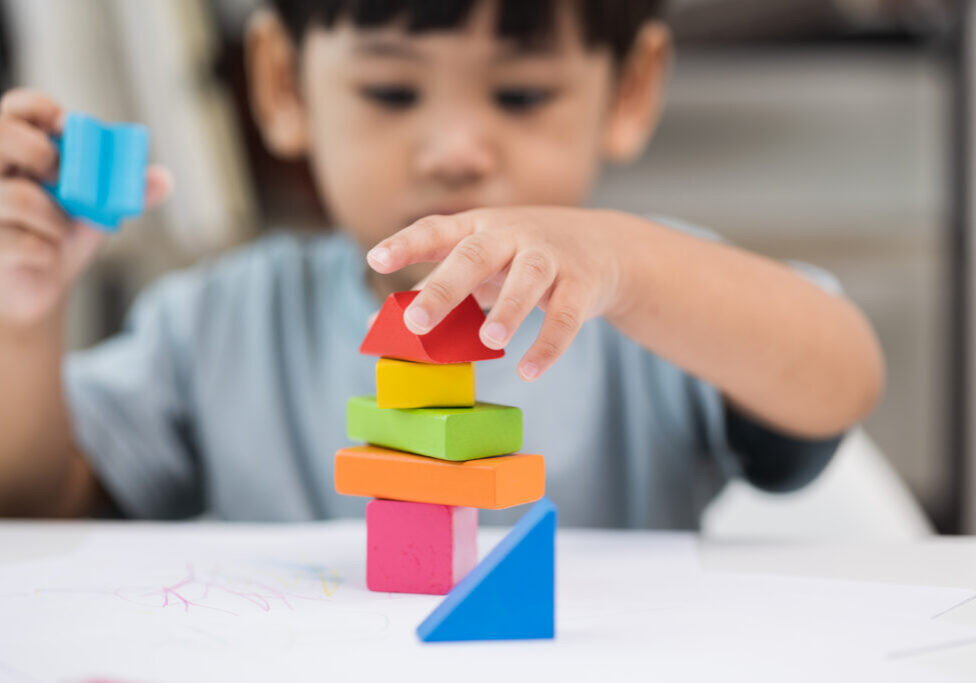 Close up Children hand Practice the skills of playing with wooden toys on the table in living room. Asian little boy education from home. Developing children's learning before entering kindergarten