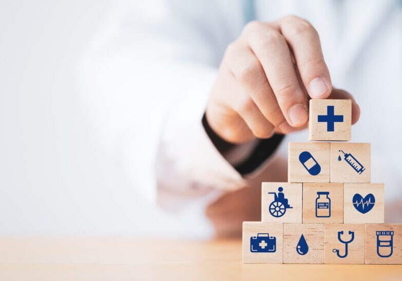 Doctor putting and stacking wooden block cube which print screen health care and medical icons for healthy and wellness concept.