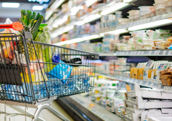 A shopping cart with grocery products in a supermarket