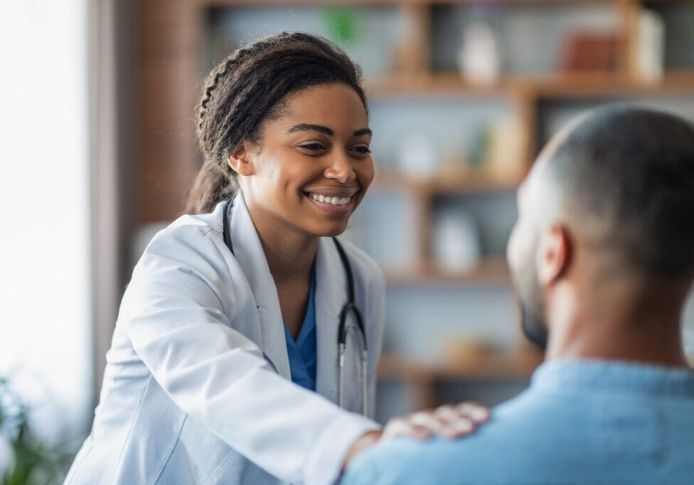 Cheerful attractive young african american woman doctor touching unrecognizable eastern man patient shoulder, general practitioner happy with results of treatment, supporting her patient, closeup