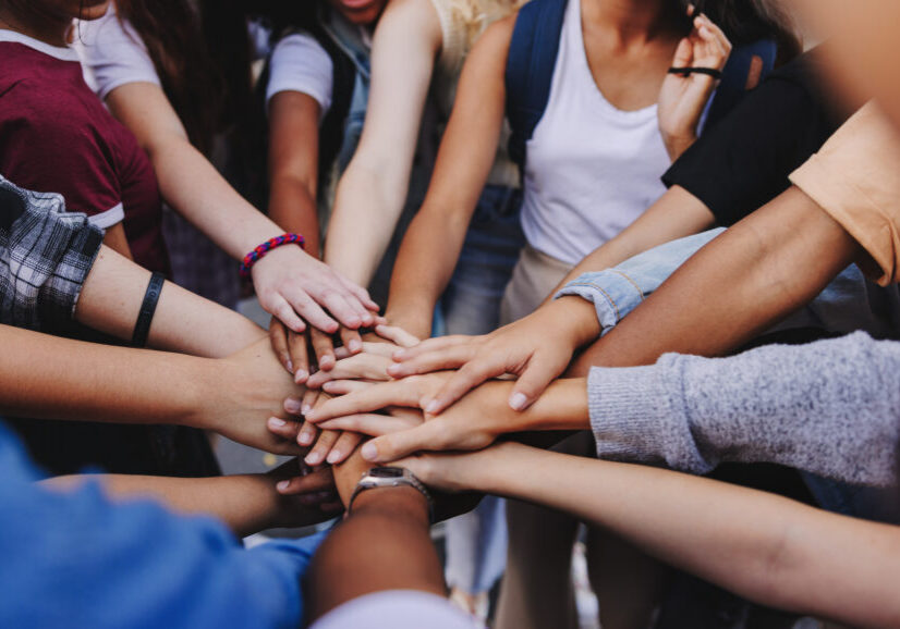 Multicultural teenagers putting their hands together in a huddle. Group of unrecognizable young people expressing their unity and teamwork