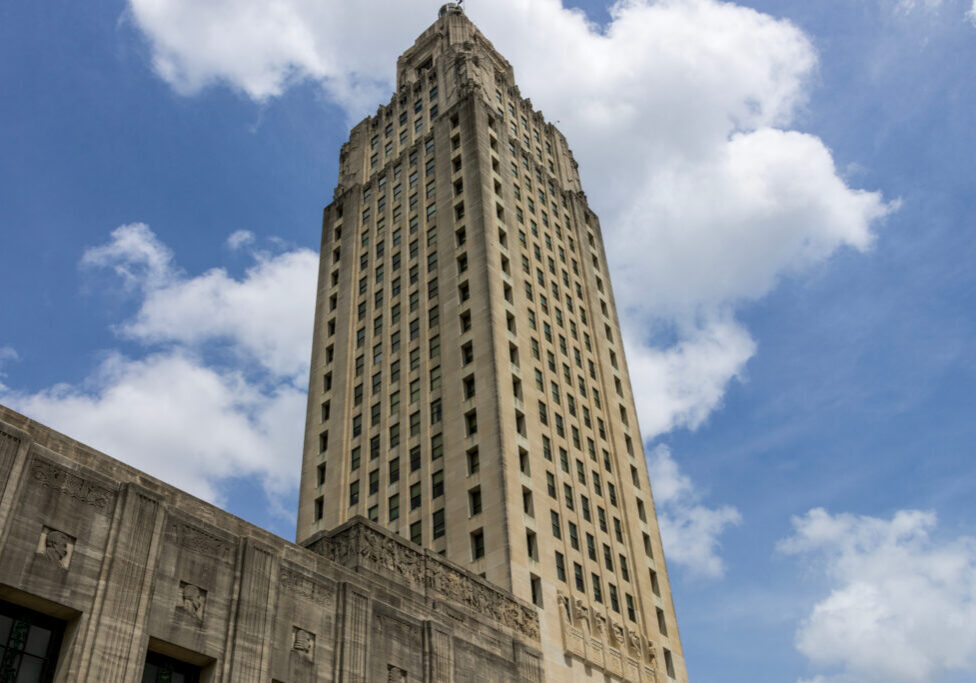 The Louisiana State Capitol building with lush green trees, blue sky and clouds in Baton Rouge Louisiana USA