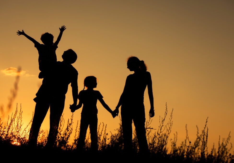 Happy family standing in the park at the sunset time.  Concept of friendly family.