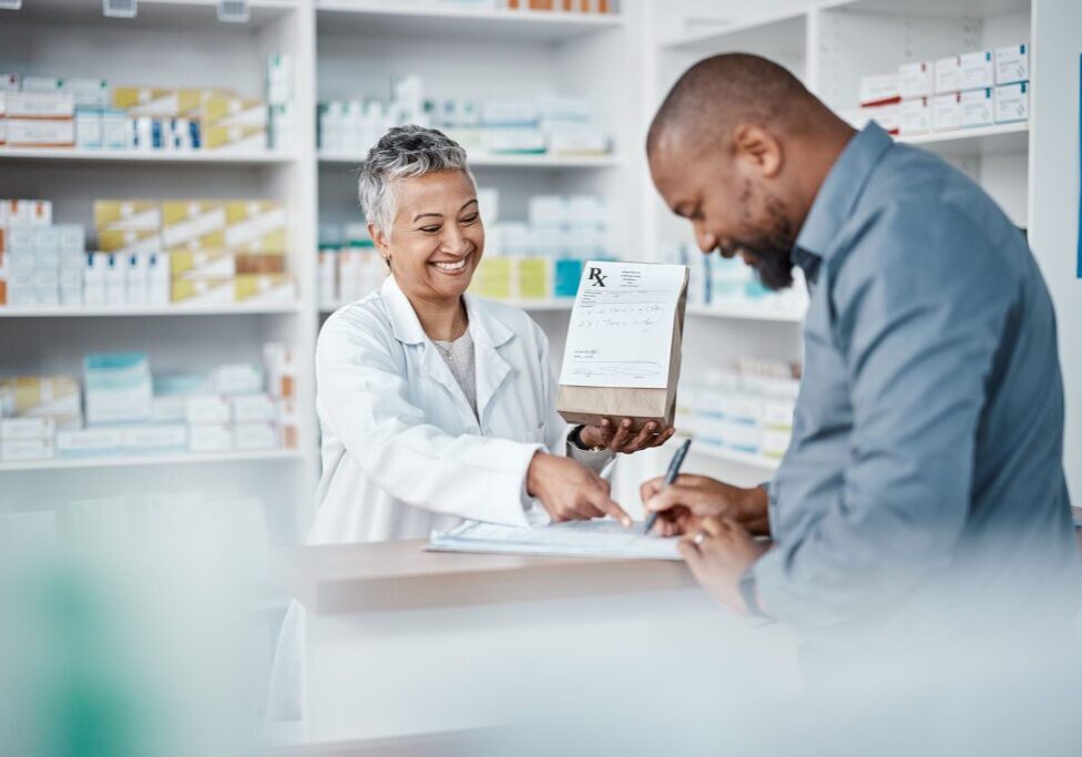 Medicine, shopping or pharmacist with customer writing personal or medical information in pharmacy. Consulting, pills or happy senior doctor helping or speaking to black man or sick African customer.